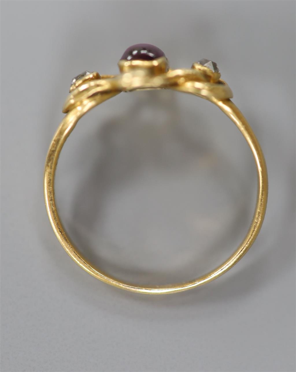 An early 20th century Arts & Crafts yellow metal, cabochon garnet and diamond set three stone ring, size O/P, gross 3 grams.